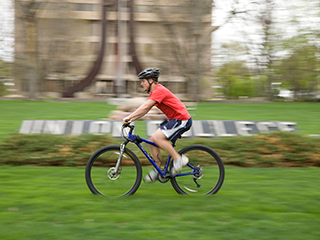 Union College student biking in front of campus